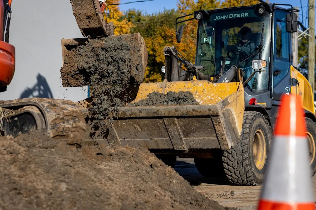 Excavatrice déposant des sols contaminés dans le godet d'une chargeuse lors de travaux de décontamination