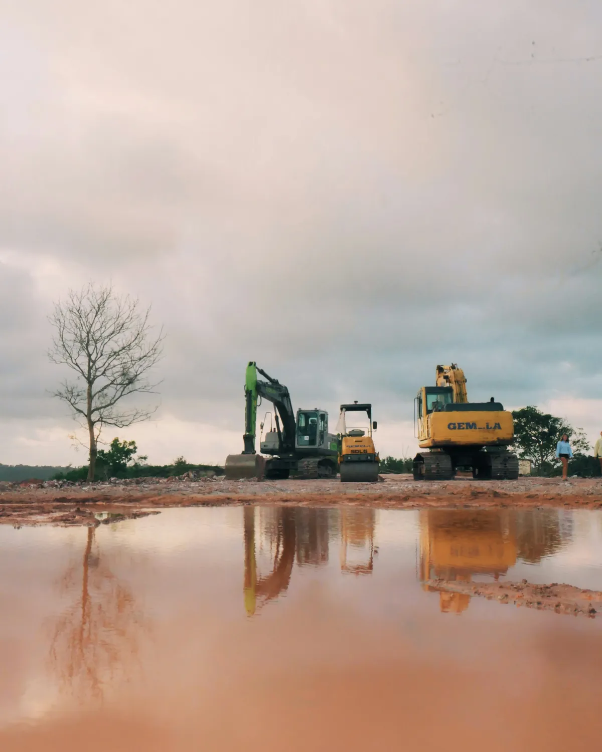 Rouleau compacteur et excavatrices sur un chantier de terrassement au sol détrempé